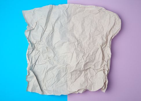 crumpled piece of gray paper on a colored background, top view, place for text