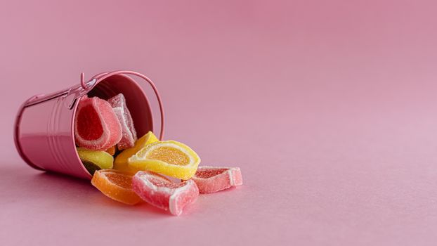 Colourful fruit Jelly candy in a pink bucket against pink background for food and snack concept