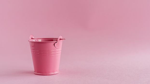 Mini colored tin pail or bucket on pink background with copy space for household items concept