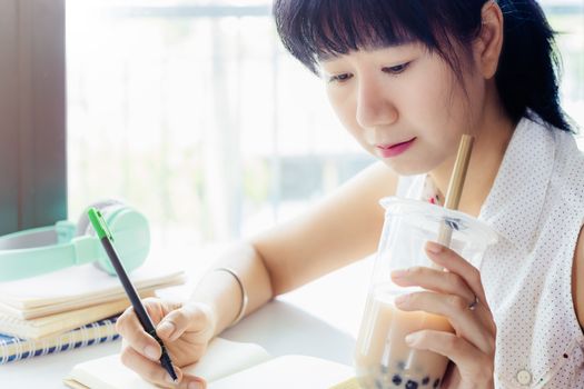 Asian woman working and drinking bubble tea with blurred background for stay at home concept