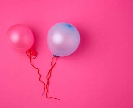 inflated blue and pink rubber balloons on a pink background, red rope