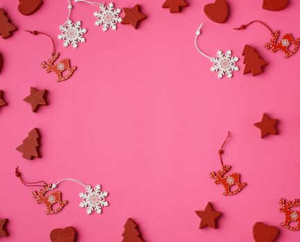 wooden carved Christmas decorations for the holiday tree on a pink background