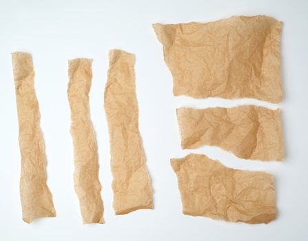 torn brown pieces of parchment paper on a white background, flat lay