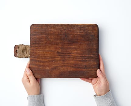 female hands holding an old empty wooden rectangular cutting board, top view, white background