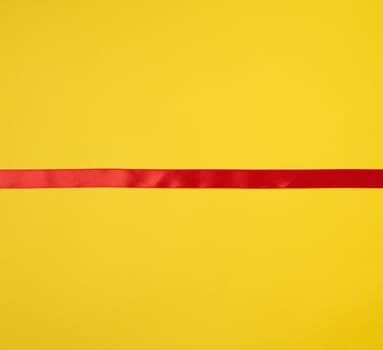red silk ribbon on a yellow background, festive backdrop, place for text