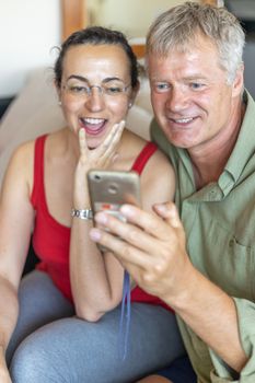 Happy middle-aged couple looking a mobile phone