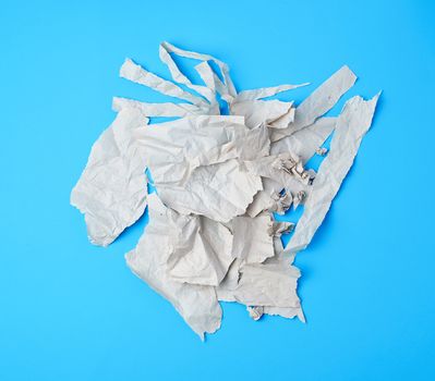 crumpled torn piece of gray paper on a blue background, close up