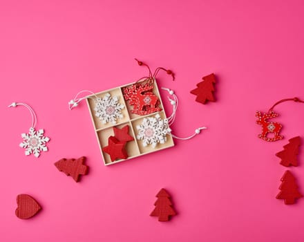wooden carved Christmas decorations for the holiday tree on a pink background, top view