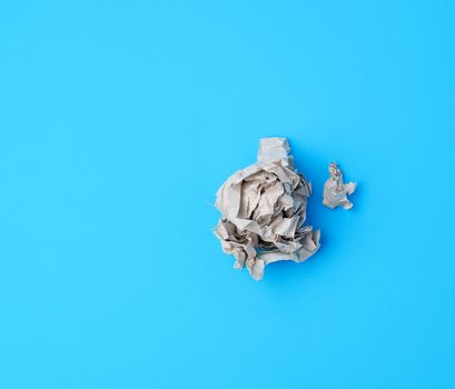 ball of crumpled gray paper on a blue background, top view