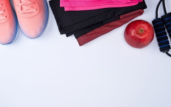 pink textile shoes and other items for fitness on a white background, top view, copy space