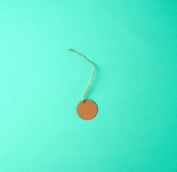 empty round brown tag on a rope, green background