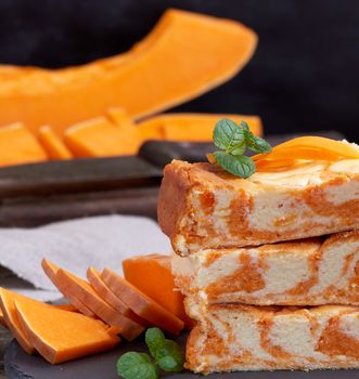 stack of square pieces of baked cheesecake cottage cheese with pumpkin and fresh pieces of vegetable