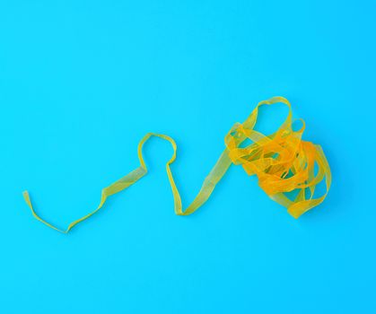 curled yellow satin ribbon on blue background, festive backdrop