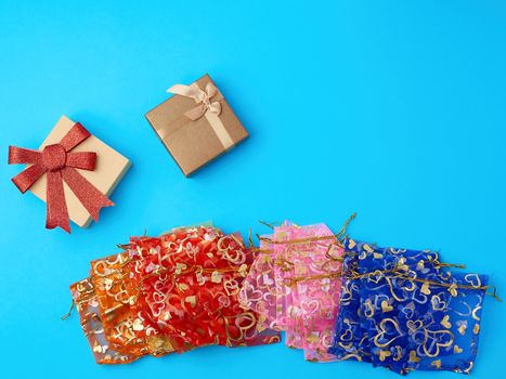 textile gift bags and cardboard boxes on a blue background, top view