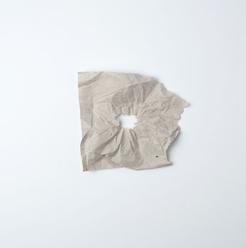 gray crumpled sheet of paper with a hole, white backing, abstract background