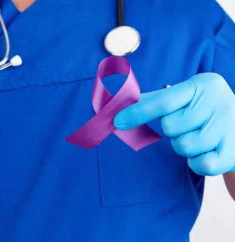 doctor in blue uniform and latex gloves holds a purple ribbon as a symbol of early research and disease control, Alzheimer's disease, cystic fibrosis, lupus, pancreatic cancer, sarcoidosis