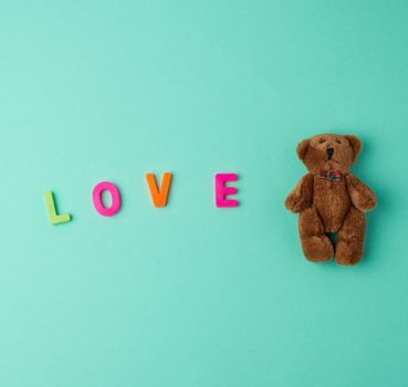 little cute brown teddy bear and the inscription love made of plastic letters