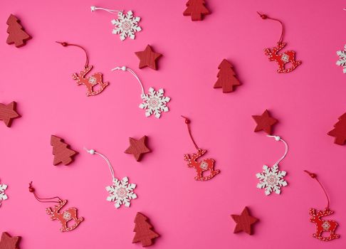 wooden carved Christmas decorations for the holiday tree on a pink background