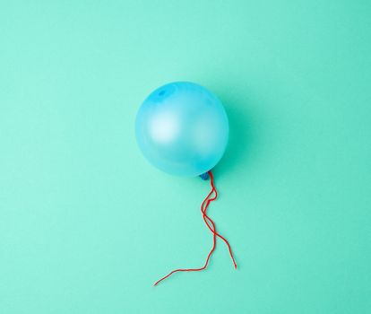 inflated blue rubber balloon on a green background, blue rope