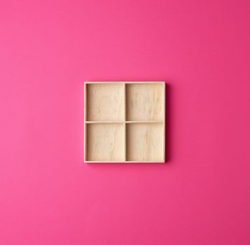 square wooden box divided into storage cells for small things on a pink background, top view