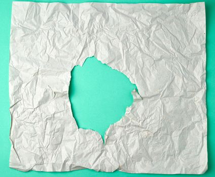 gray crumpled sheet of paper with a hole, green backing, abstract background