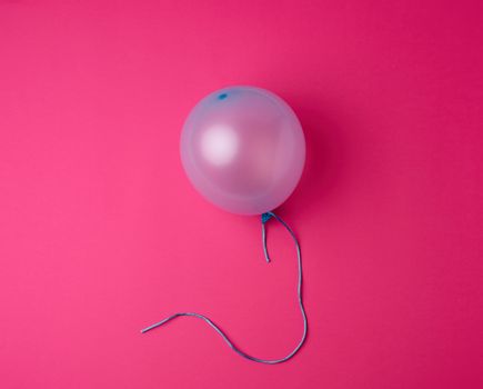 inflated blue rubber balloon on a pink background, blue rope