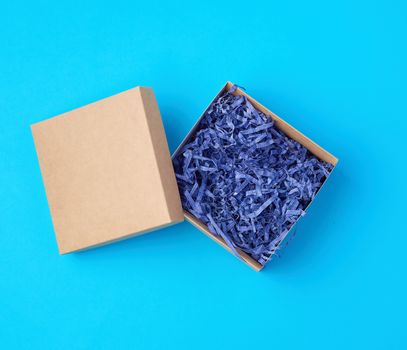 open empty brown craft box on a blue background, top view, holiday backdrop 