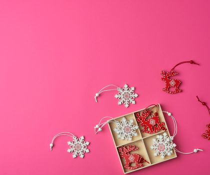 wooden carved Christmas decorations for the holiday tree on a pink background, copy space