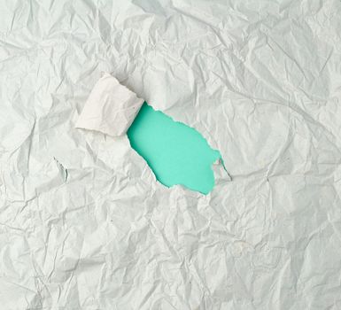 gray crumpled sheet of paper with a hole, green backing, abstract background