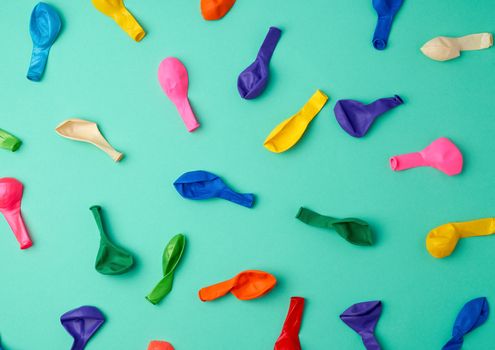 many deflated latex colorful balloons scattered on a green background, festive backdrop