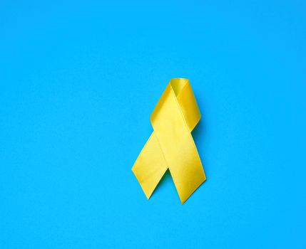 yellow ribbon on a blue background, symbol of the fight against the cat's tumor, problem of suicides and their prevention, close up