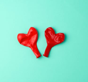 two red rubber balloons blow away in the shape of a heart on a green background