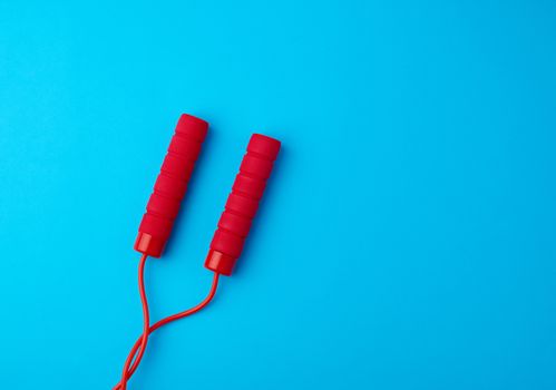fragment of red rope for sports on a blue background, two neoprene handle