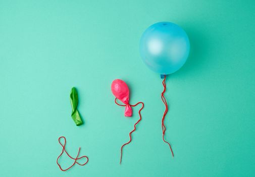 blue inflated and deflated rubber balls and red rope on a green background