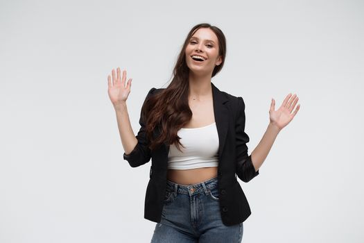 Cheerful excited surprised successful young female wearing pink blazer over black top showing ten with fingers and looking at camera