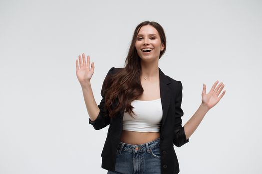 Cheerful excited surprised successful young female wearing pink blazer over black top showing ten with fingers and looking at camera