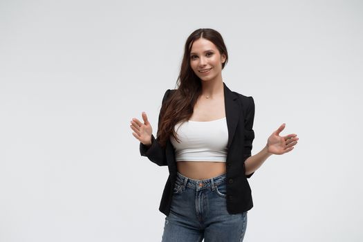 Positive optimistic young female in casual clothes gesturing and showing big size with hands while standing against white background