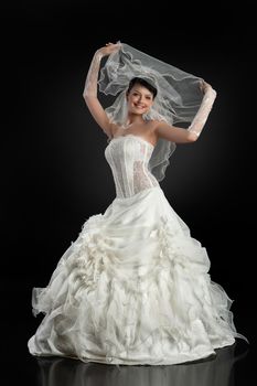 Young beautiful woman in a wedding dress on a studio background