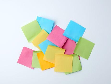pile of multicolored paper square stickers on white background, top view