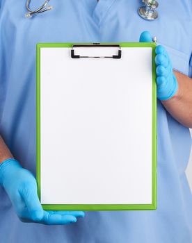 doctor in blue uniform and latex gloves holds a blue holder for sheets of paper, empty space for writing text, white background