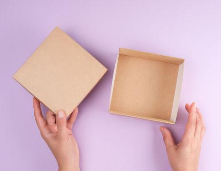 girl opens a brown square box on a purple background, top view, concept of giving gifts