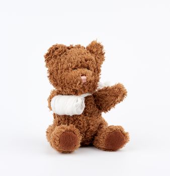 brown teddy bear with rewound white bandage paw on a white background, pediatrics concept