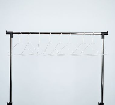 empty white metal hangers hang on a chrome bar, white background, close up