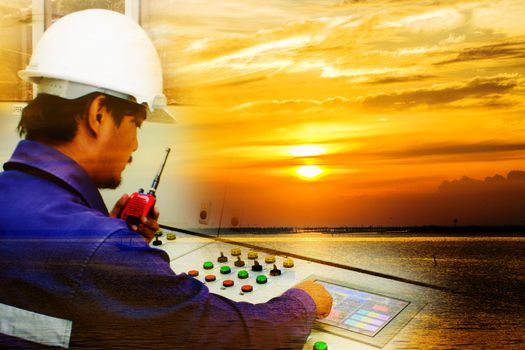 Double Exposure of engineer working in control room and beautiful orange sky with sunset over the sea