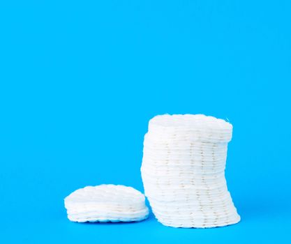 stack of white cotton round discs for cosmetic procedures on a blue background