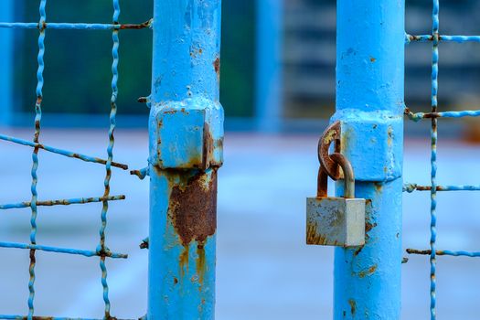 Opened blue soccer field gate with key lock