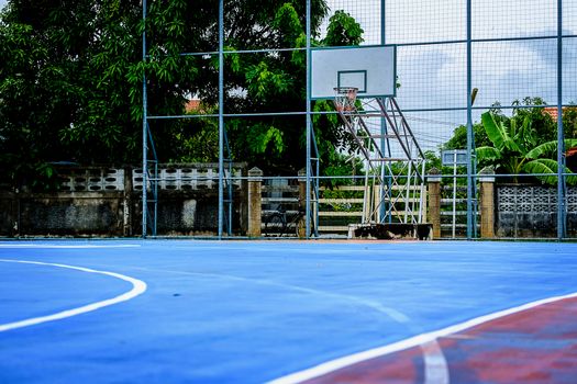 Outdoor public basketball court with blue playground rubber