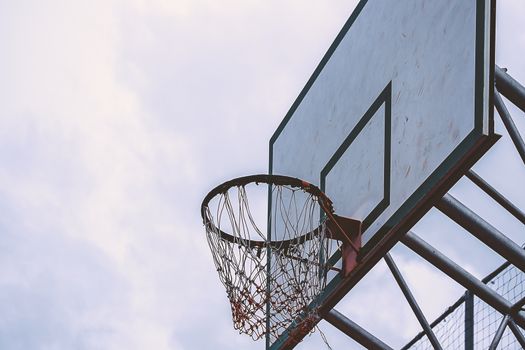 Basketball hoop in a blue day and overcast sky, added color filter