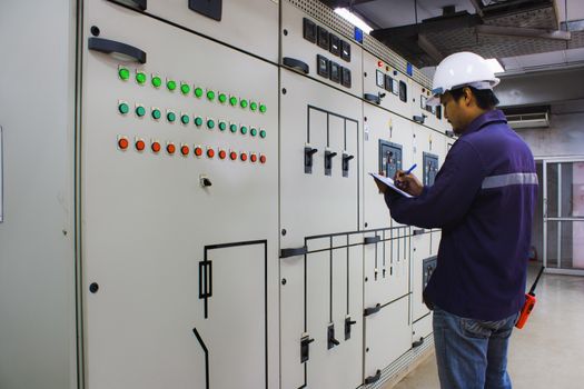 Engineer checking and monitoring the electrical system in the control room