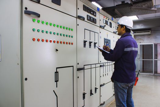 Engineer checking and monitoring the electrical system in the control room